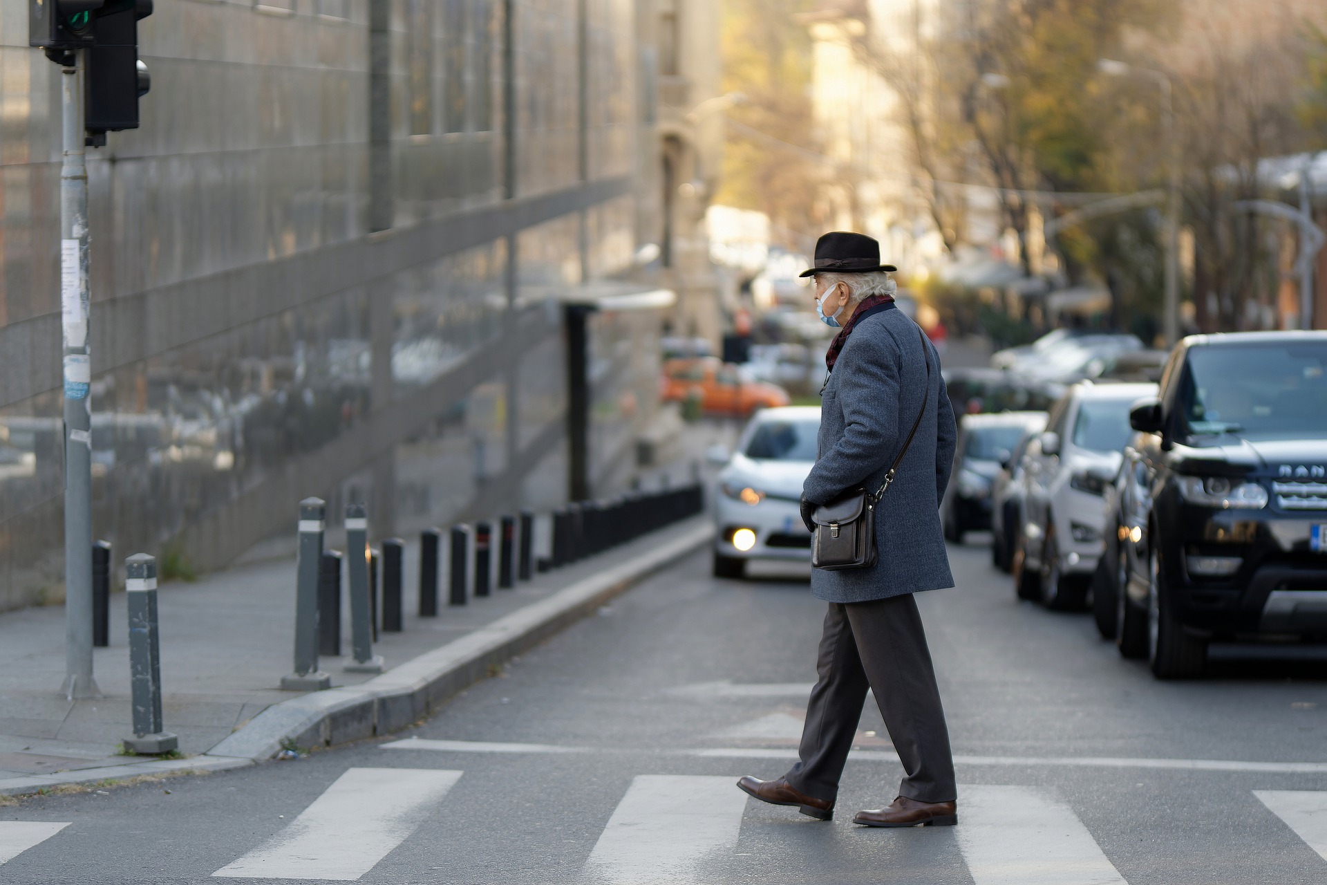 An elderly man crossing the street at a crosswalk.
