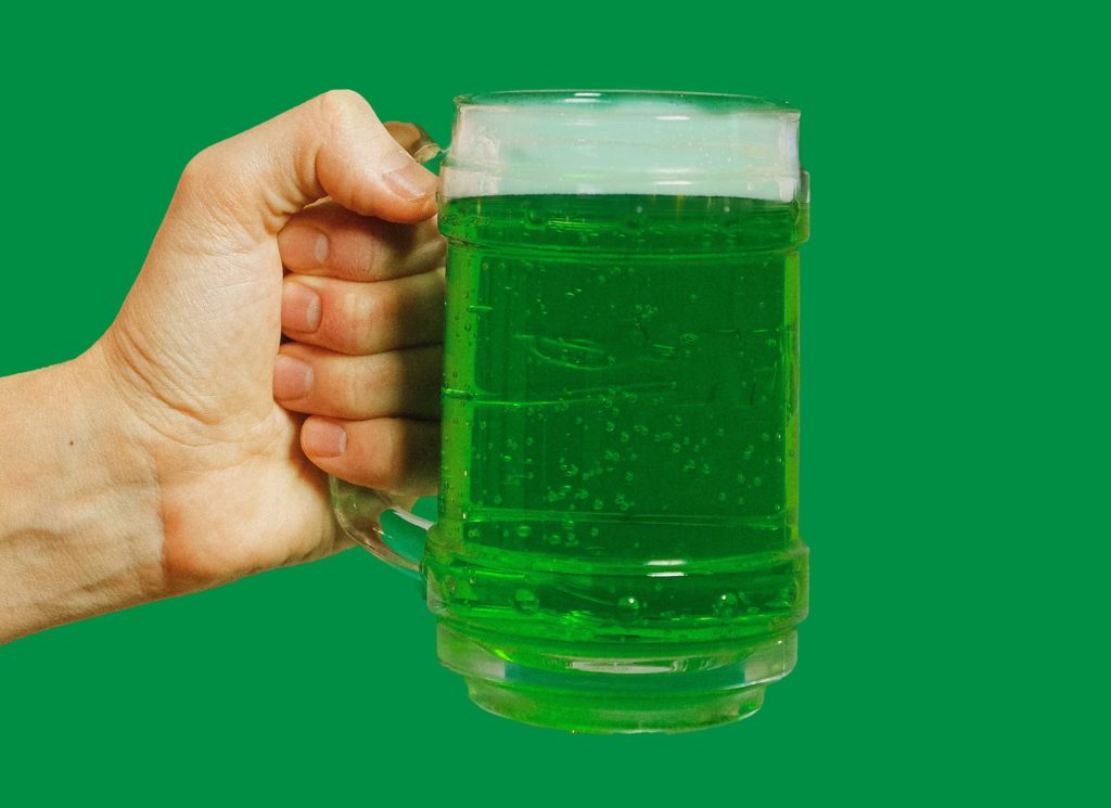 green beer being held with a green background