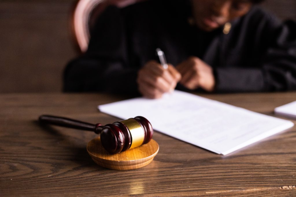 faceless judge signing a paper behind a gavel